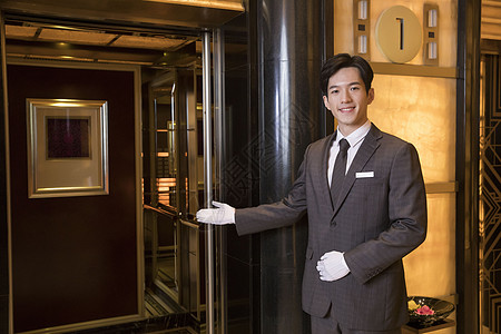 酒店服务员为顾客开电梯背景图片