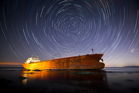 搁浅的船水面上的星轨银河背景
