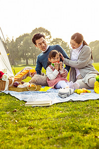 亲子游玩一家人欢乐地在草坪野餐背景