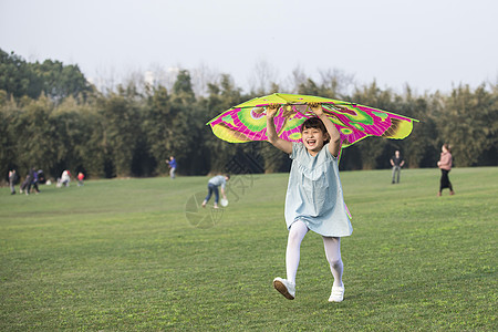 躺在草坪上小女孩拿着风筝在草坪上奔跑背景