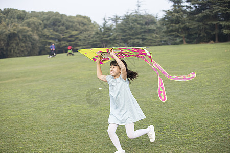 小女孩拿着风筝在草坪上奔跑图片