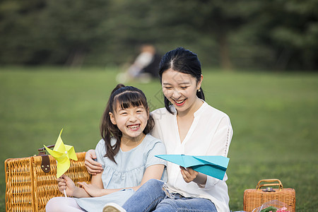 妈妈和女儿在草坪上玩纸飞机高清图片