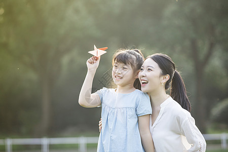 胶棒和纸飞机妈妈和女儿在草坪上玩纸飞机背景