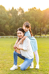 阳光拥抱妈妈和女儿在草地玩耍背景