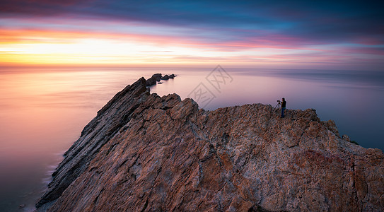 夕阳下摄影师海岸风光背景