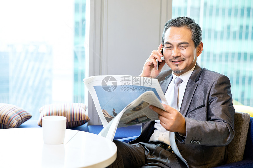 商务男性看报纸打电话图片