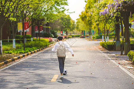 背书包的小男孩小男孩放学踢足球背景