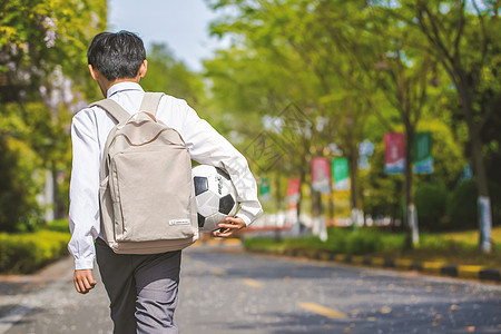 背书包小男孩小学生放学踢足球背景