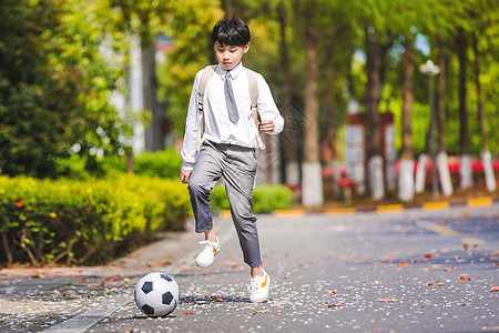 背书包的小男孩小学生放学踢足球背景