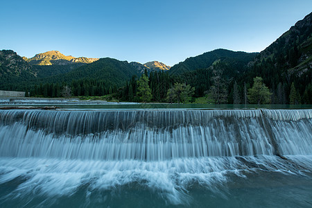 高山树林新疆天池景区日落背景