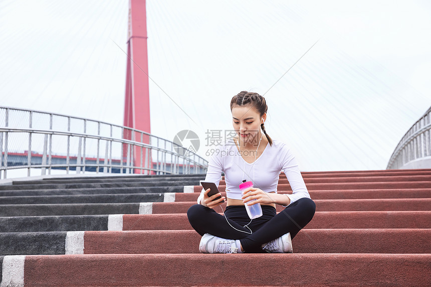 运动女性休息玩手机图片