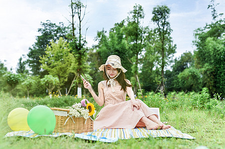 草地上坐着玩耍的美女图片