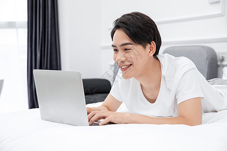男青年卧室床上用电脑背景图片