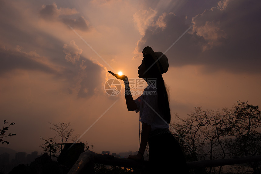 夕阳下女孩手托太阳剪影照片图片