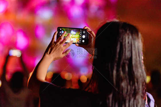 潮流美女用手机在音乐节拍照图片