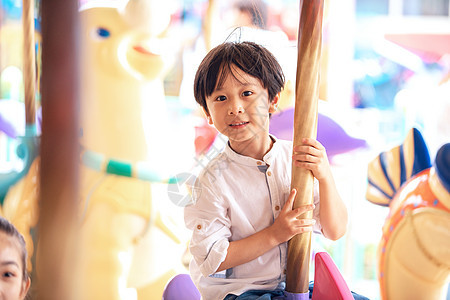 小男孩在游乐场坐旋转木马背景图片
