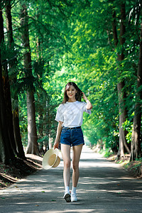 女孩走在林荫小道上图片