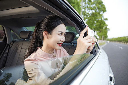 年轻女性在车内用手机拍照图片