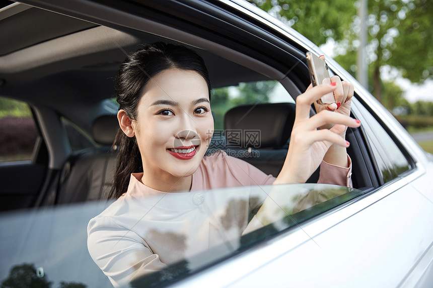 年轻女性在车内用手机拍照图片