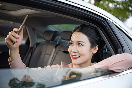 年轻女性在车内用手机拍照图片