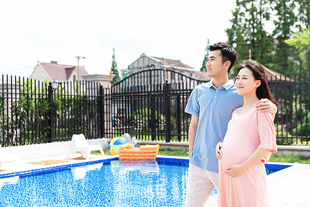 丈夫和孕妇一起站在户外泳池旁图片