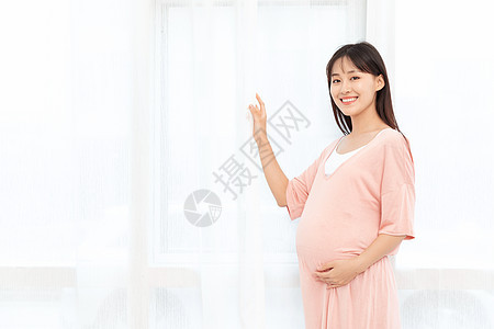 一个孕妇在客厅站着抚摸肚子背景图片