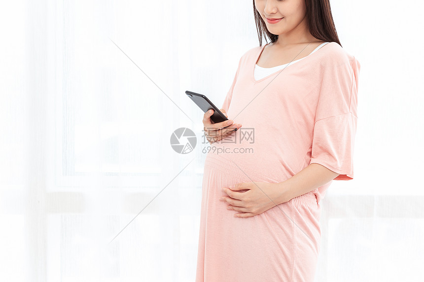 孕妇在客厅纱窗旁边使用手机图片