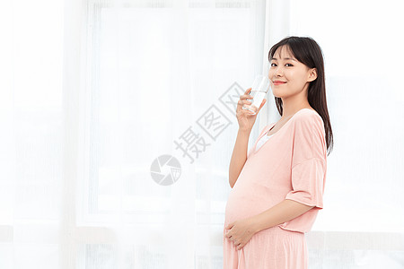 一个孕妇站着在客厅喝水背景图片