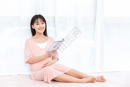 孕妇看书孕妇在纱窗旁边侧腿坐着看书阅读背景