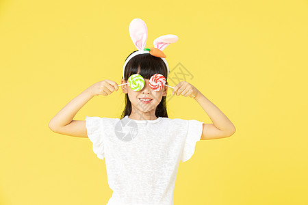 戴着兔耳朵的小女孩拿着糖果高清图片
