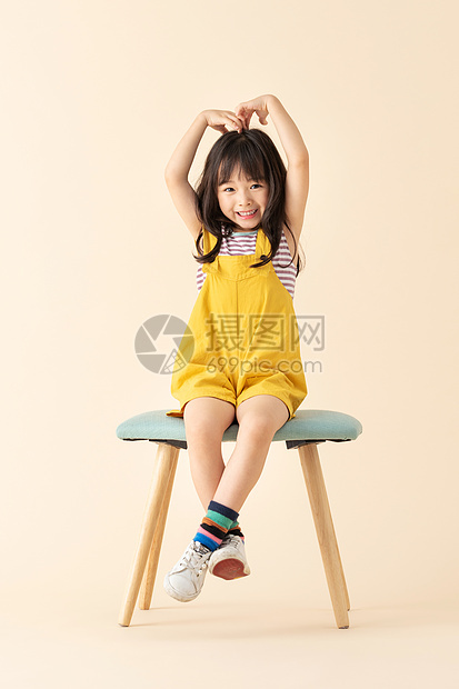 可爱小女孩坐在椅子上比心图片