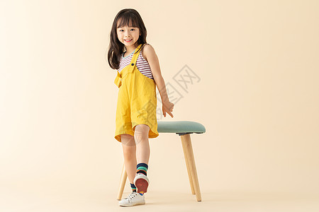 小女孩微笑可爱小美女在站在椅子旁边背景