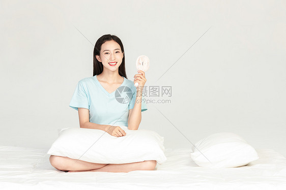 女性坐在床上吹小风扇图片