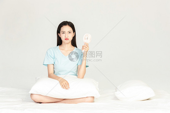 女性坐在床上吹小风扇图片