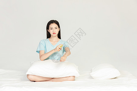 美女坐在床上用驱蚊水图片