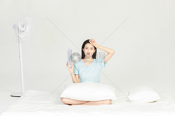 女生拿着温度计坐在床上图片
