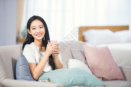 女性坐在沙发上喝水背景图片
