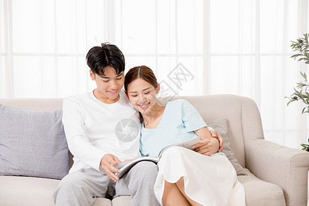 夫妻情侣坐在沙发上一起看书背景
