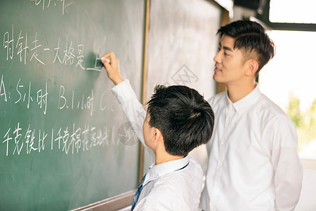 老师和学生微笑着在黑板上做题背景图片