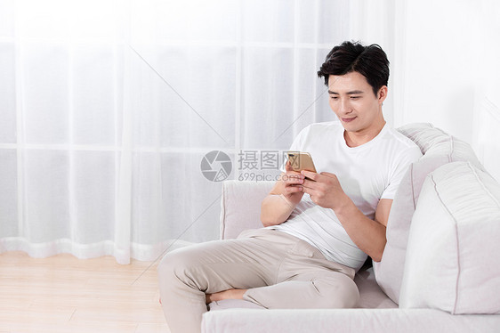 男性坐在沙发上玩手机图片