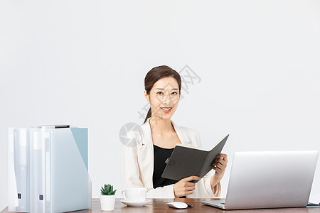 坐在办公桌前看文件的商务女性图片