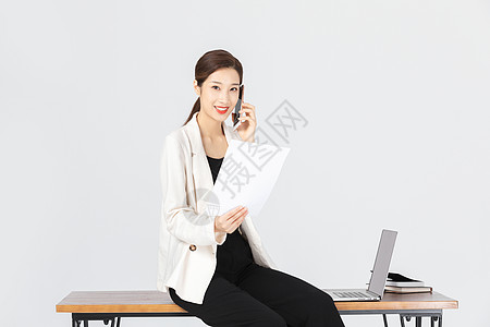 坐在办公桌前拿着白纸的商务女性图片