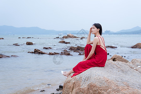 海中岩石上的美女深圳较场尾海边礁石上的红衣少女侧影背景