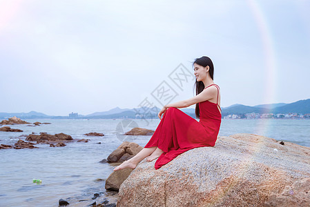 海中岩石上的美女深圳较场尾海边礁石上的红衣少女背景