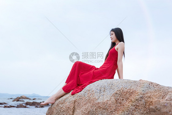 坐在深圳较场尾海边礁石上的红裙子少女图片
