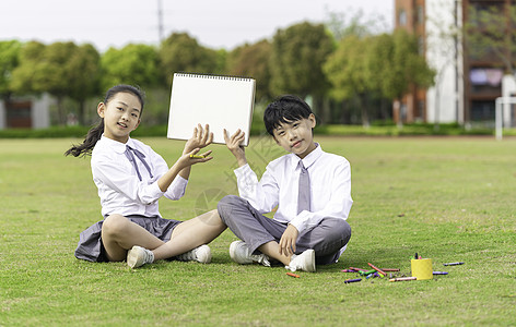 画画的学生学生坐在草地上拿着画板背景