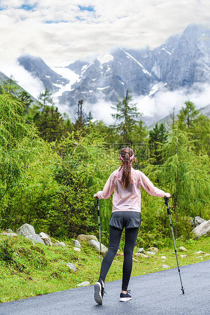 女孩手持登山杖背影图片