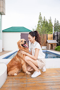 年轻美女主人与宠物金毛犬嬉戏图片