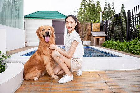 年轻美女与宠物狗院子里嬉戏图片