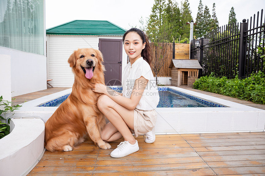 年轻美女与宠物狗院子里嬉戏图片